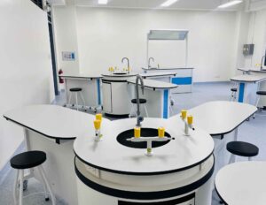 A fully equipped chemistry laboratory with modern apparatus, safety equipment, and students conducting experiments.